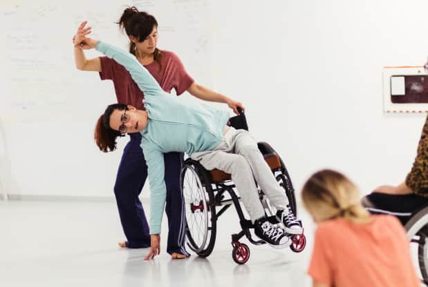 Dos mujeres bailando una de ellas en silla de ruedas