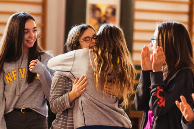 Chicas jóvenes abrazandose una de ellas con síndrome de down