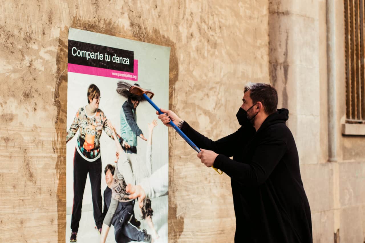 hombre pegando un cartel en la pared con una escoba